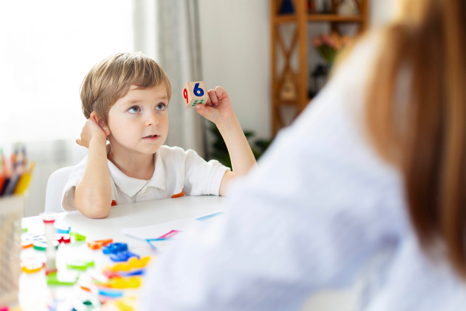 Little boy with number block at table learning math. Early education and cognitive development concept. Design for educational material, banner.